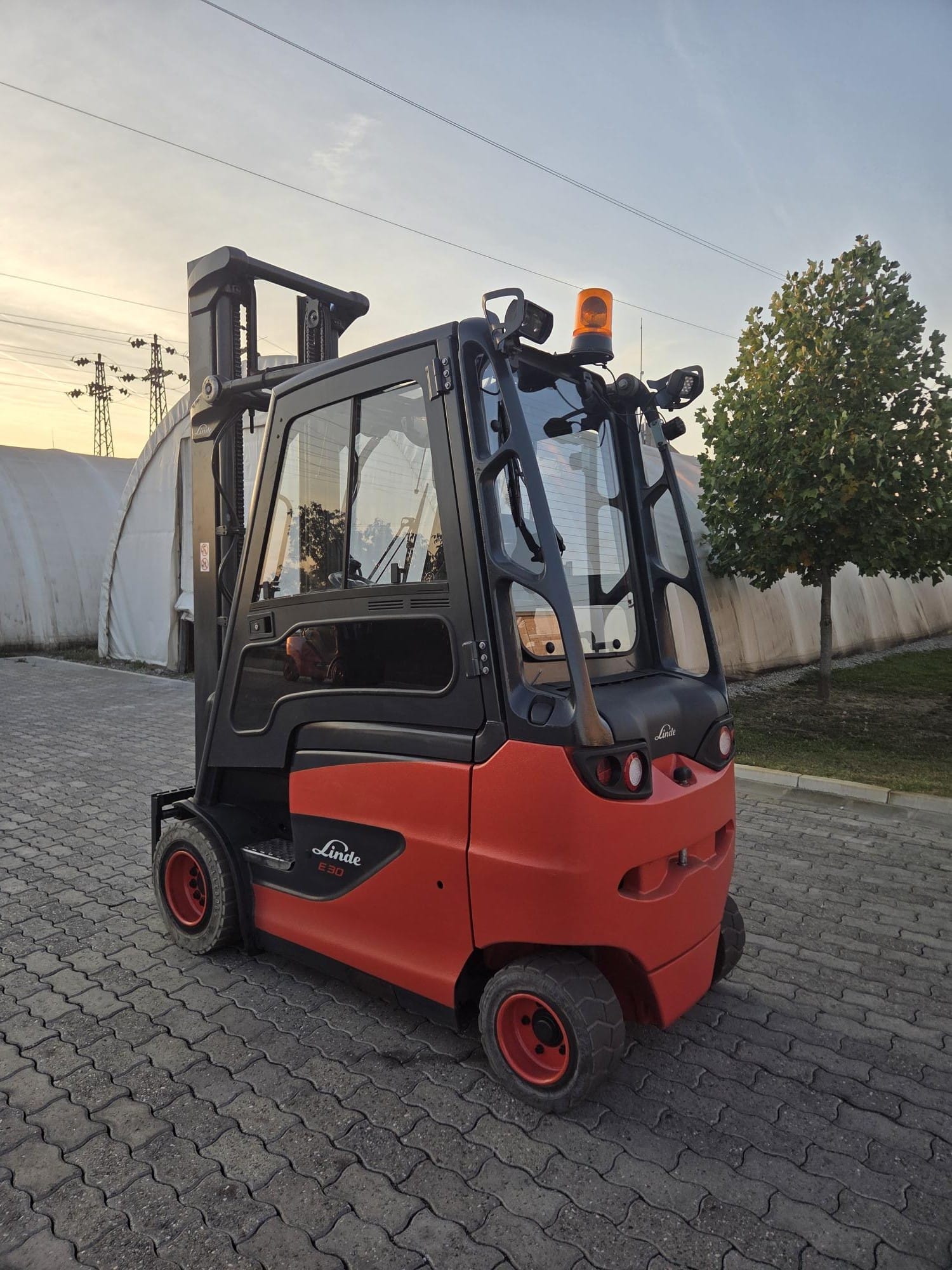 Linde E30H-01 — zadnji ugao, rotaciono svetlo i radni farovi | Jović Viljuškari Polovni viljuškar Linde E30H-01 straga, zatvorena kabina sa rotacionim svetlom i zadnjim radnim farovima